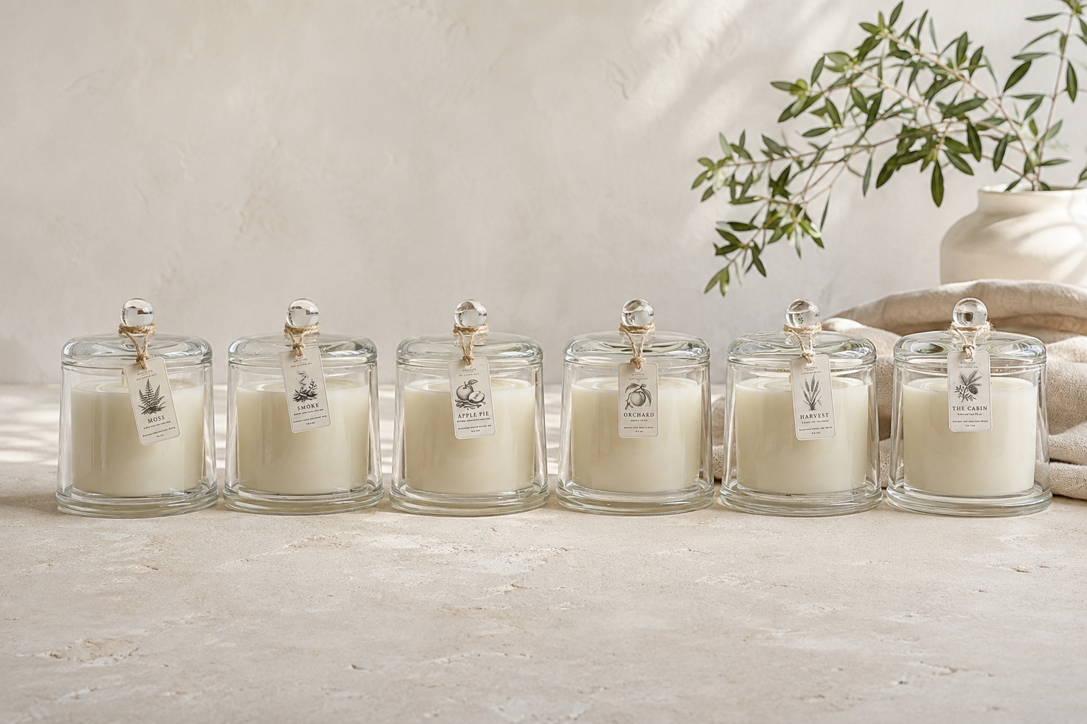 The complete Ember Edit collection of six reusable glass cloche candles with botanical hang tags