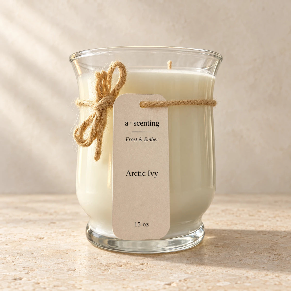 Arctic Ivy 15 oz Frost & Ember candle with cream hangtag, photographed on warm ivory stone.